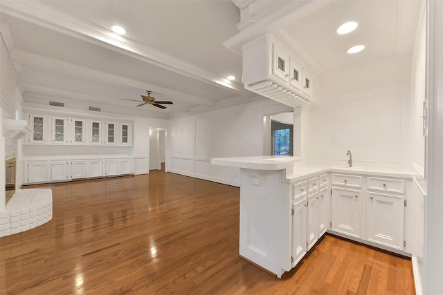 kitchen featuring a peninsula, white cabinetry, ceiling fan, wood finished floors, and open floor plan