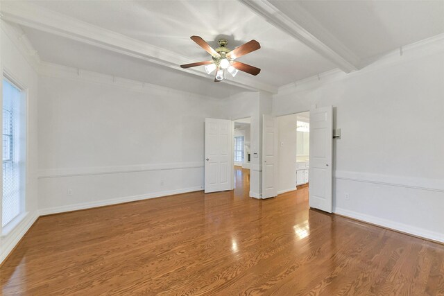 empty room featuring ceiling fan, wood finished floors, ornamental molding, beamed ceiling, and baseboards