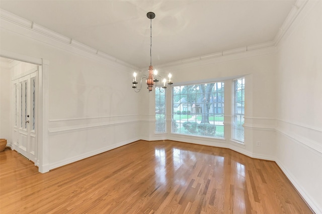 unfurnished dining area with a chandelier, wood finished floors, and crown molding
