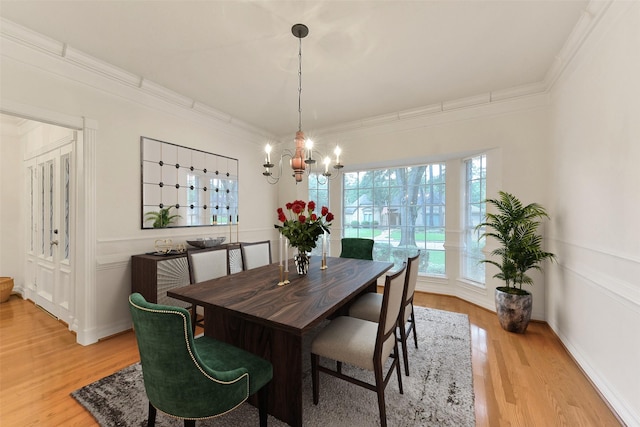dining space featuring a chandelier, light wood-style flooring, and crown molding