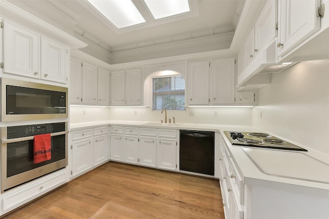 kitchen featuring black appliances, a sink, white cabinets, and light wood-type flooring