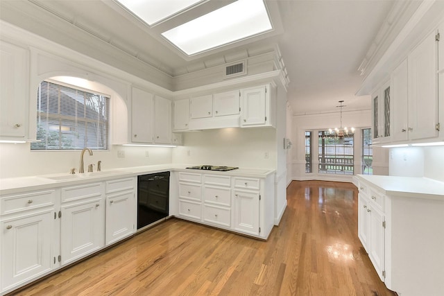 kitchen with a sink, black appliances, light wood finished floors, white cabinets, and ornamental molding