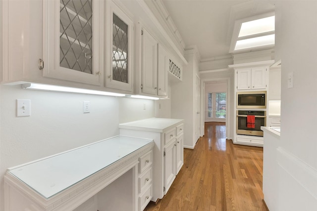 hallway with light wood finished floors and ornamental molding