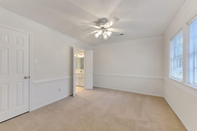 spare room with a ceiling fan, light colored carpet, ornamental molding, and baseboards