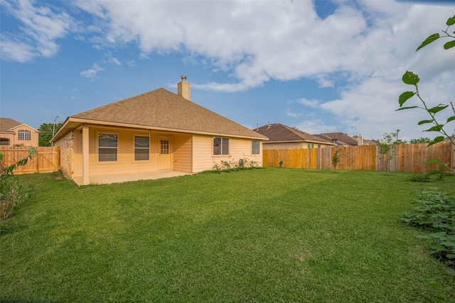 back of property with a chimney, a patio area, and roof with shingles