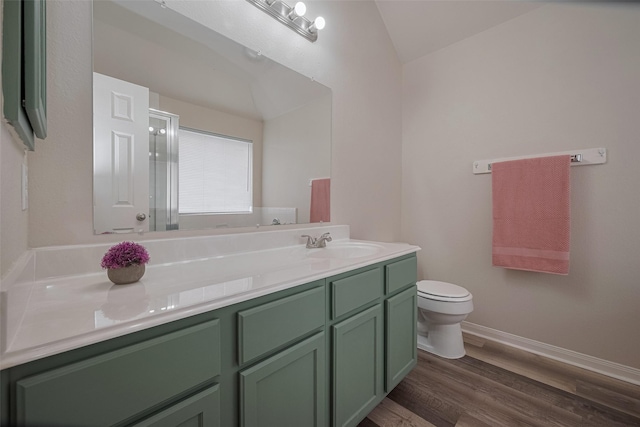 bathroom with wood finished floors, lofted ceiling, toilet, vanity, and baseboards