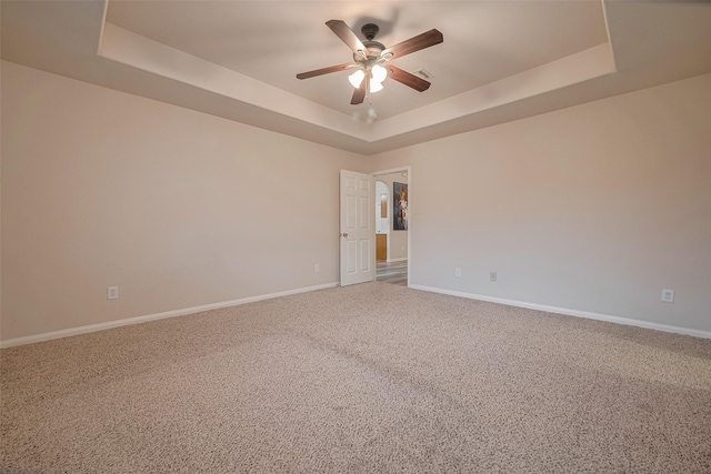 carpeted empty room with a raised ceiling, ceiling fan, and baseboards