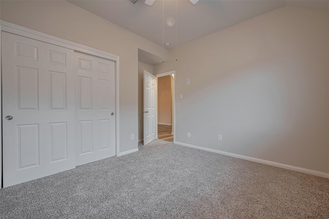 unfurnished bedroom with carpet flooring, baseboards, a closet, ceiling fan, and vaulted ceiling