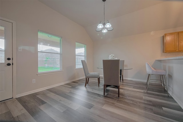 dining space featuring a chandelier, wood finished floors, vaulted ceiling, and baseboards