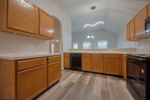 kitchen with black appliances, a sink, light wood-type flooring, tasteful backsplash, and light countertops