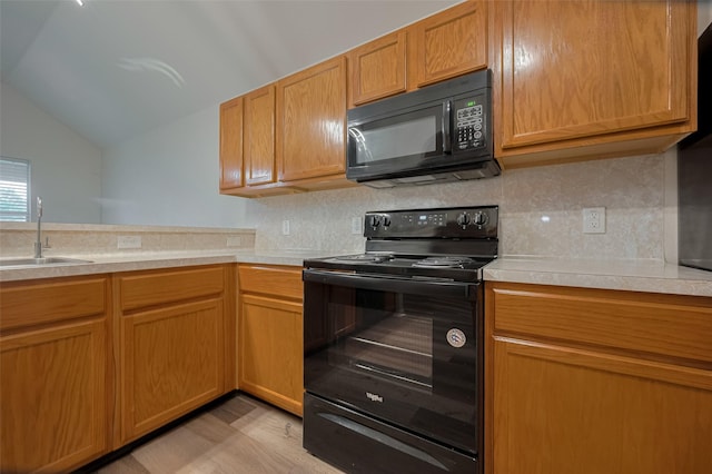 kitchen featuring black appliances, a sink, lofted ceiling, light countertops, and backsplash