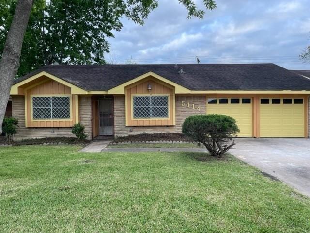 ranch-style home featuring a garage, driveway, a front yard, brick siding, and board and batten siding