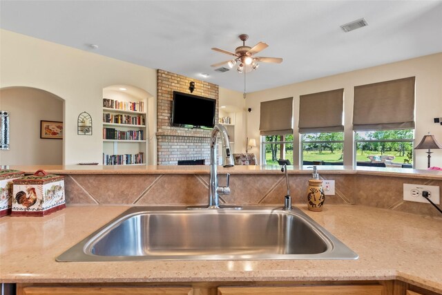 11413 7th St, Santa Fe, TX 77510 - kitchen featuring open floor plan, a sink, ceiling fan, a brick fireplace, and light stone countertops