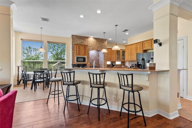 11413 7th St, Santa Fe, TX 77510 - kitchen featuring black fridge with ice dispenser, built in microwave, tasteful backsplash, glass insert cabinets, and a kitchen bar
