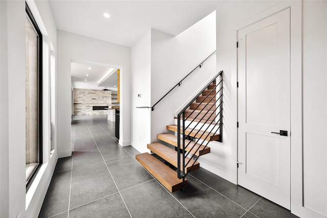 stairway featuring a large fireplace, recessed lighting, baseboards, and tile patterned floors