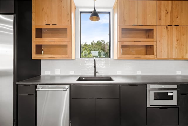 kitchen featuring a sink, dark countertops, appliances with stainless steel finishes, backsplash, and modern cabinets