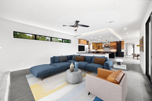 tiled living room with recessed lighting, a sink, ceiling fan, and baseboards