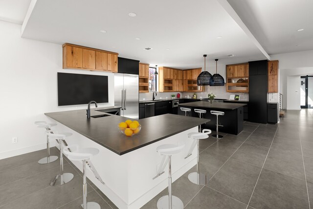 kitchen featuring built in fridge, open shelves, dark countertops, a kitchen bar, and recessed lighting