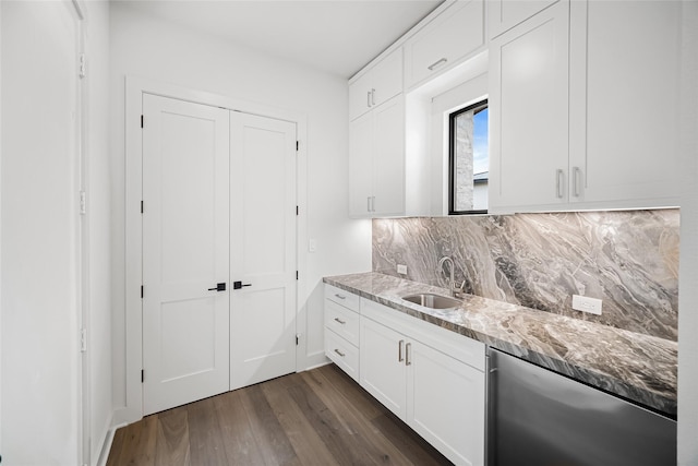 kitchen with a sink, light stone counters, tasteful backsplash, dark wood-style floors, and white cabinets