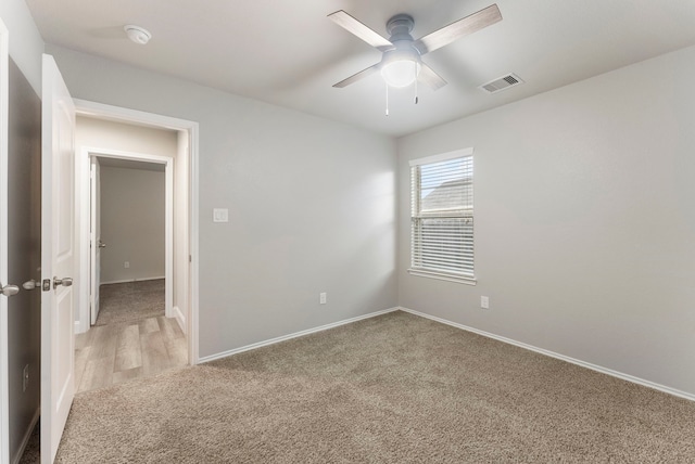 empty room featuring light colored carpet, a ceiling fan, baseboards, and a smoke detector