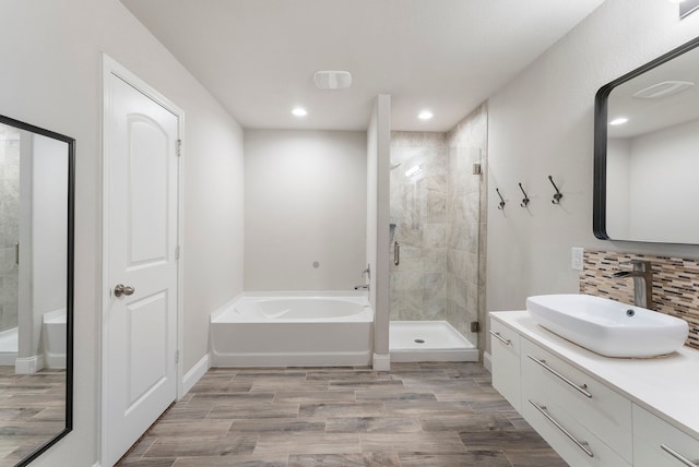 bathroom featuring a bath, a stall shower, vanity, wood finished floors, and recessed lighting