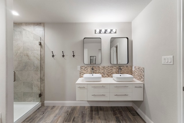bathroom with a stall shower, backsplash, wood finish floors, and double vanity