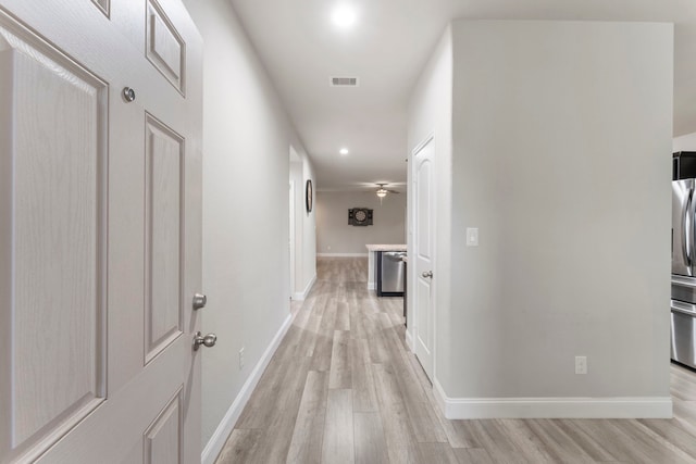corridor featuring light wood-type flooring, baseboards, and recessed lighting