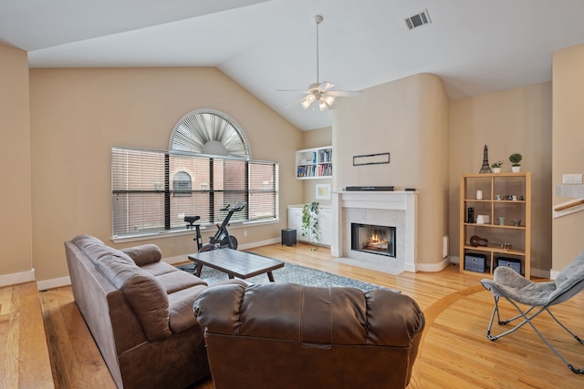 living room with wood finished floors, a ceiling fan, a fireplace, baseboards, and vaulted ceiling