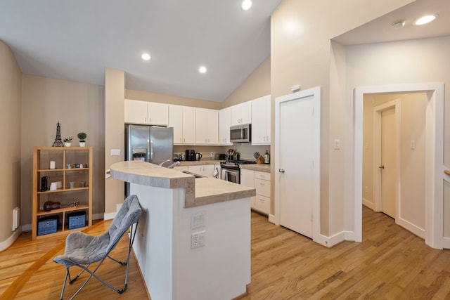 kitchen with stainless steel appliances, a sink, light countertops, light wood-style floors, and white cabinetry