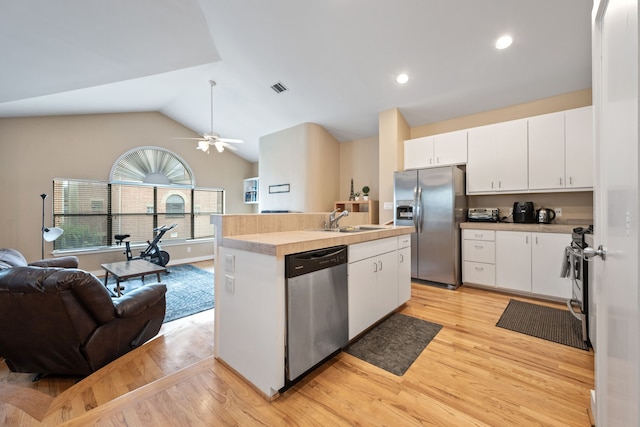 kitchen with stainless steel appliances, open floor plan, light wood-style floors, an island with sink, and a sink