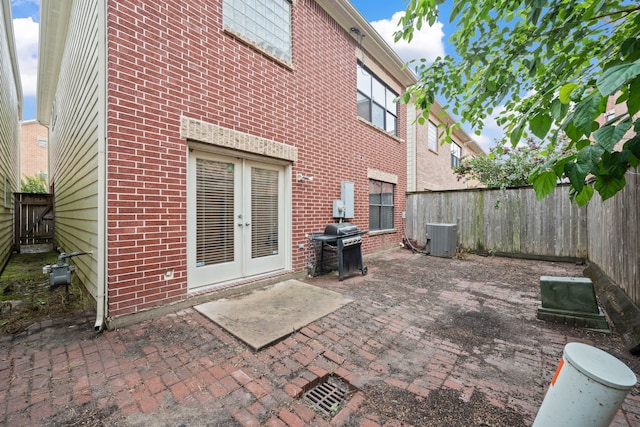rear view of house with french doors, brick siding, a patio, and a fenced backyard
