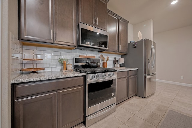 4314 Reese Ravine Ln, Katy, TX 77493 - kitchen featuring stainless steel appliances, tasteful backsplash, dark brown cabinets, light tile patterned floors, and baseboards