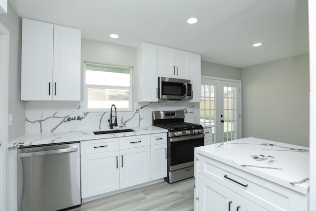 5506 Karelian Dr, Houston, TX 77091 - kitchen with appliances with stainless steel finishes, a sink, backsplash, light stone countertops, and white cabinetry