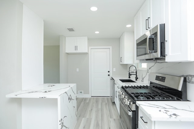 5506 Karelian Dr, Houston, TX 77091 - kitchen featuring appliances with stainless steel finishes, a sink, light stone countertops, recessed lighting, and white cabinetry