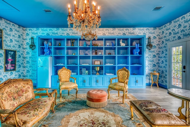 living area with wallpapered walls, a chandelier, wood finished floors, and baseboards