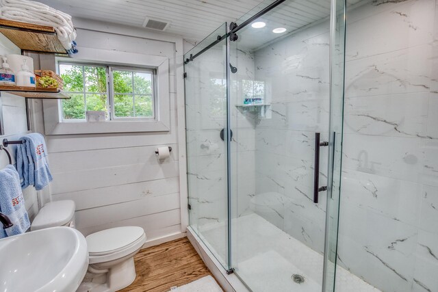 full bath featuring wood finished floors, toilet, a marble finish shower, and a sink