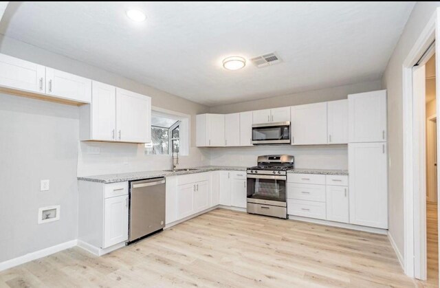 148 Seaside Ln, Texas City, TX 77590 - kitchen featuring appliances with stainless steel finishes, white cabinetry, light wood-type flooring, a sink, and recessed lighting