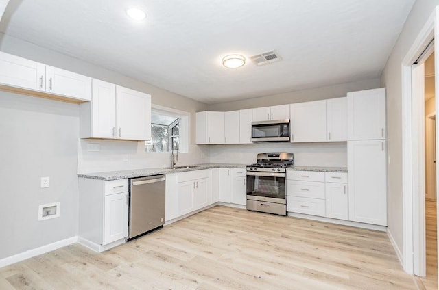 148 Seaside Ln, Texas City, TX 77590 - kitchen with appliances with stainless steel finishes, a sink, light wood-style floors, white cabinetry, and recessed lighting