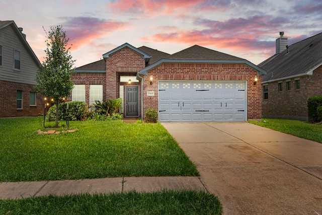 traditional-style home featuring brick siding, driveway, a yard, an attached garage, and a shingled roof