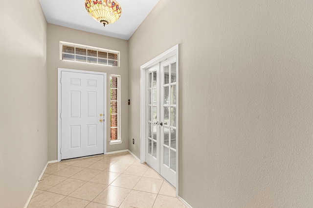 foyer entrance with french doors, light tile patterned floors, and baseboards