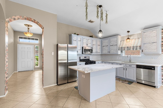 kitchen with stainless steel appliances, a sink, light tile patterned floors, backsplash, and vaulted ceiling
