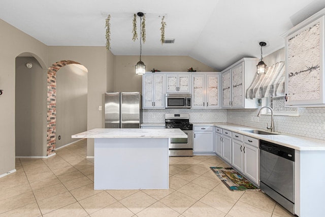 kitchen with stainless steel appliances, a sink, a center island, decorative backsplash, and lofted ceiling