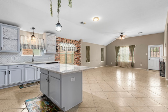 kitchen featuring a sink, light tile patterned flooring, a ceiling fan, decorative light fixtures, and a center island