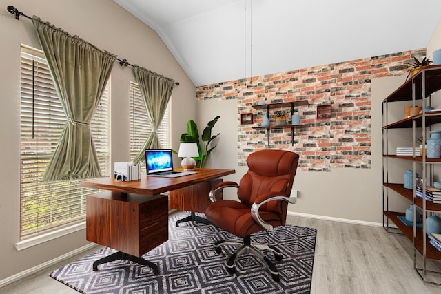 office space with wood finished floors, lofted ceiling, baseboards, and brick wall
