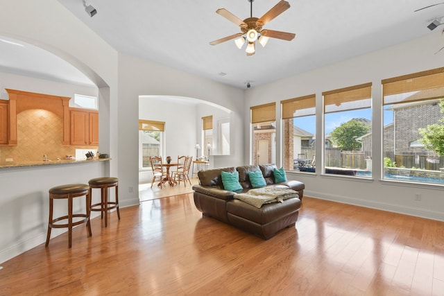 8611 Springmere Ct, Houston, TX 77095 - living room featuring arched walkways, a ceiling fan, light wood-type flooring, and baseboards