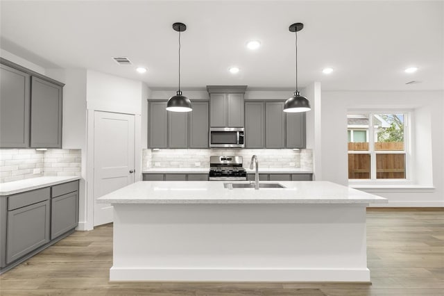 8307 Red Shiner Way, Fulshear, TX 77441 - kitchen with appliances with stainless steel finishes, gray cabinets, a sink, decorative backsplash, and a center island with sink