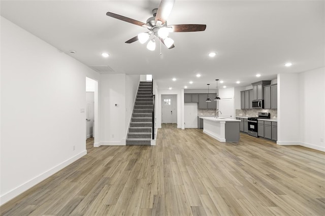 8307 Red Shiner Way, Fulshear, TX 77441 - unfurnished living room featuring a ceiling fan, stairs, light wood-type flooring, baseboards, and recessed lighting