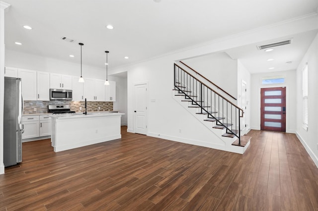 13415 Scott St, Houston, TX 77047 - kitchen featuring appliances with stainless steel finishes, tasteful backsplash, light countertops, a kitchen island with sink, and dark wood-style floors