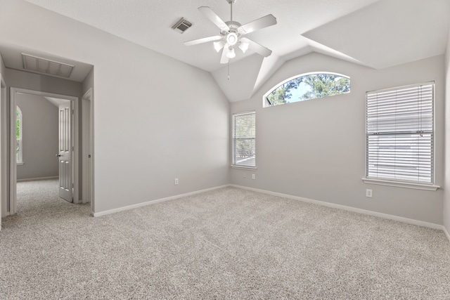 carpeted empty room featuring a ceiling fan, vaulted ceiling, baseboards, and attic access