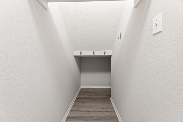 staircase with wood finished floors, baseboards, and a textured wall